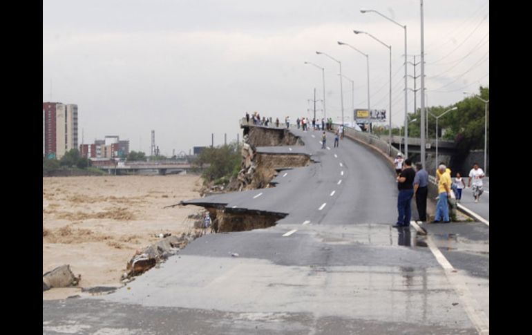 Varias personas observan la destrucción que causó la corriente del Río Santa Catarina en un paso elevado en Monterrey. REUTERS  /