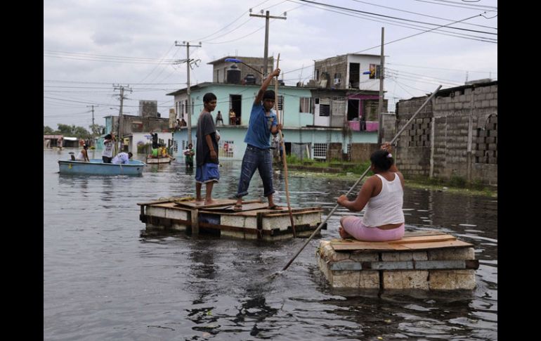 Personas cruzan las calles en albercas de fibra de vidrio y objetos habilitados como balsas provisionales por inundaciones. REUTERS  /