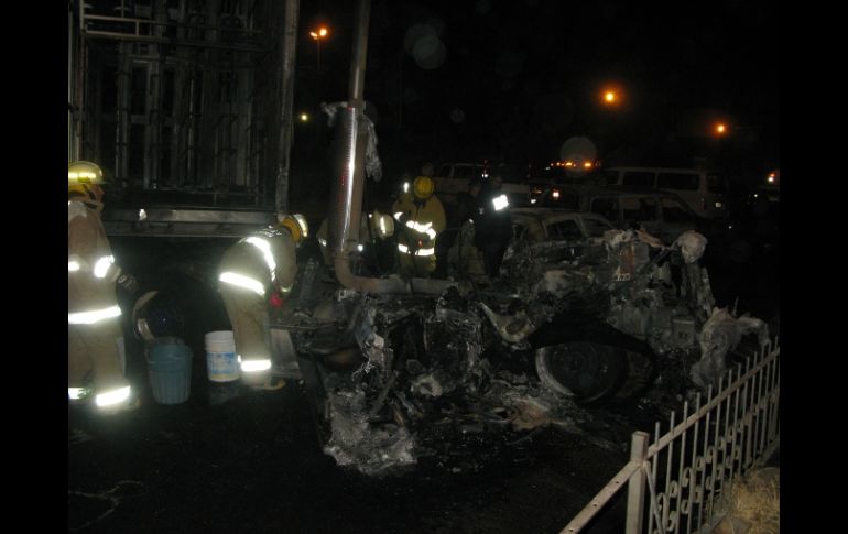 Bomberos limpian la zona en la que fueran incendiados en Carretera a Chapala tres vehículos, la noche del sábado. M. PATIÑO  /