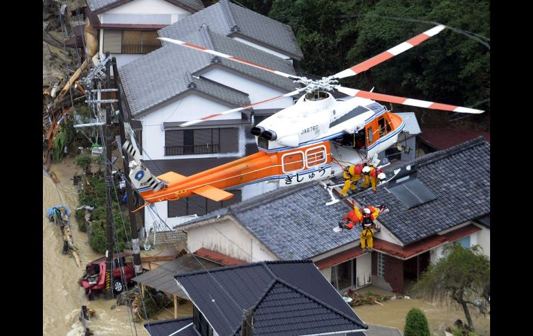Miembros de la tripulación de un helicóptero de rescate ayudan a una persona aislada por un tifón. AP  /