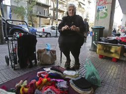 Una mujer teje diversos objetos que después vende en una calle del centro de Atenas, Grecia. EFE  /