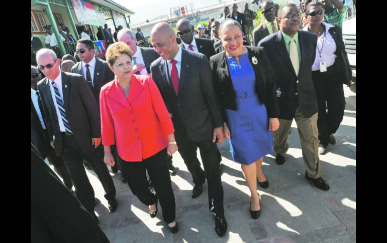 La mandataria brasileña, Dilma Rousseff (i), pasea por las calles de Puerto Príncipe con su homólogo haitiano Michel Martelly (c). AFP  /