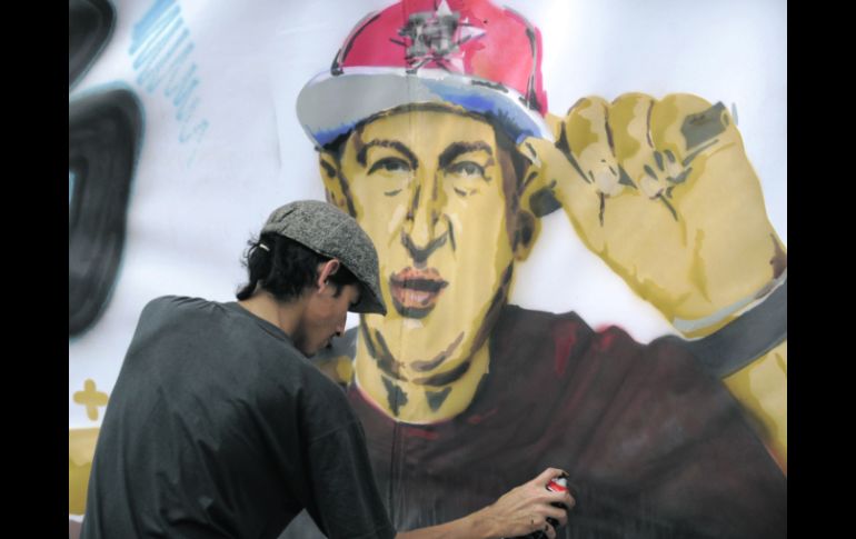 Un hombre da los últimos toques a un dibujo de Chávez, durante un acto en que seguidores le desearon pronta recuperación. AFP  /