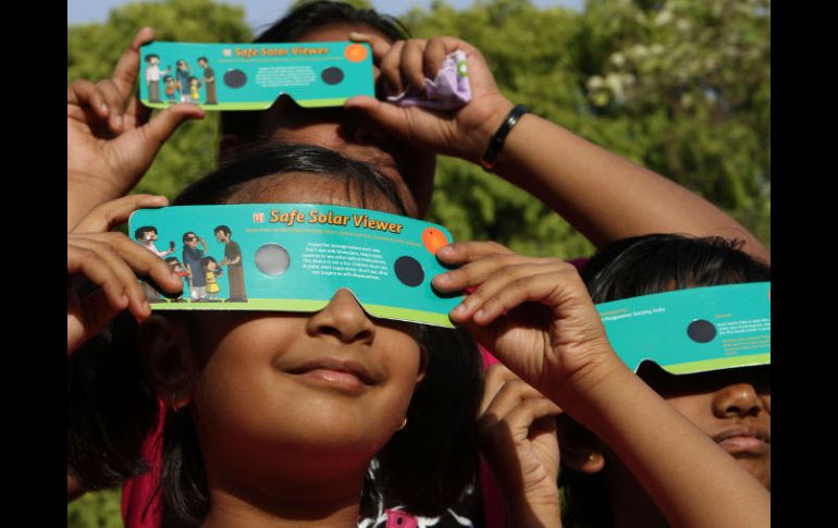 Niñas observan con aditamentos adecuados un eclipse de sol, ilustrando cómo proteger la vista para observar este fenómeno. AP  /