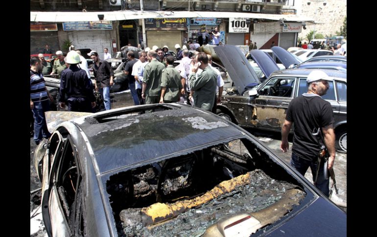 Varias personas observan los daños en los vehículos tras una fuerte explosión registrada en Dmasco. EFE  /