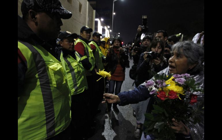 Una de las participantes en la marcha obsequia flores a los policías que realizan el cerco. REUTERS  /