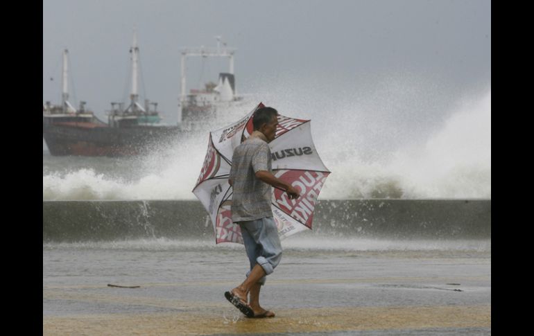 Un hombre camina por la costa mientras las altas olas causadas por el tifón rompen en la orilla. REUTERS  /