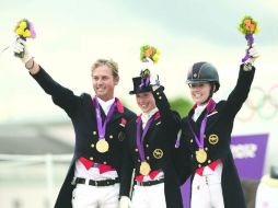 Carl Hester, Laura Bechtolsheimer y Charlotte Dujardin celebran el primer lugar tras recibir su medalla de oro. XINHUA  /