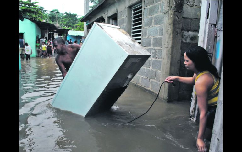 A RESGUARDO. Personas afectadas por una inundación en La Barquita, municipio de Santo Domingo Este, rescatan algunos bienes. EFE  /