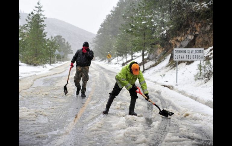 Elementos de Protección Civil limpian hoy una carretera en la Sierra de Arteaga, en Coahuila, donde cayó una nevada. EFE EFE /