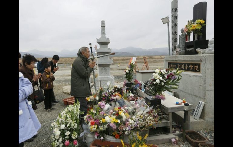 Miembros de una familia en Ishinomaki, oran por los fallecidos en el tsunami, un día antes de el segundo aniversario de la tragedia. EFE /