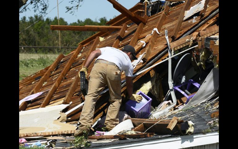 Un hombre trata de rescatar algunas de sus propiedades de su casa, destruida por el tornado. EFE /