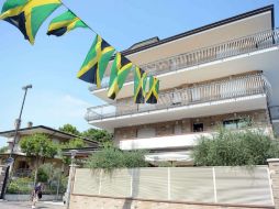 Banderas de Jamaica cuelgan de un balcón del hotel Fra I Pini, donde los atletas jamaicanos se encuentran alojados. AP /