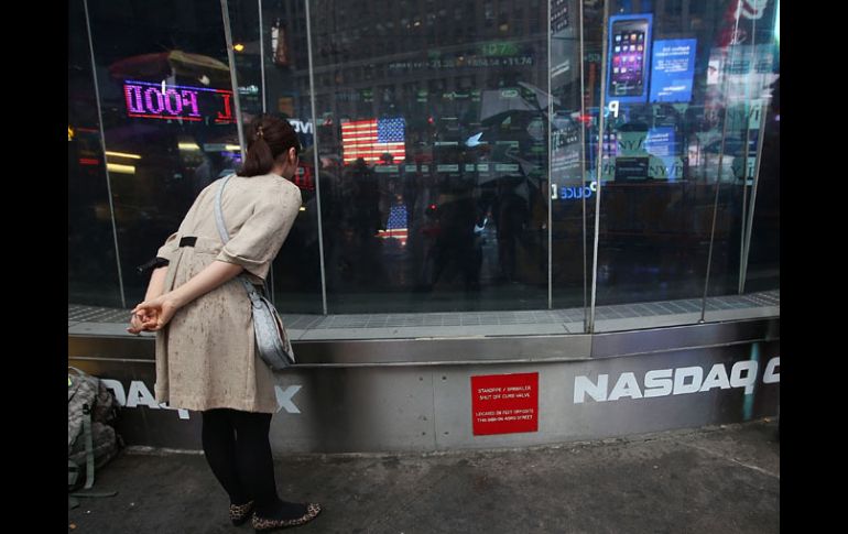 Una mujer observa a través de una ventana las pantallas en negro del índice Nasdaq. AFP /