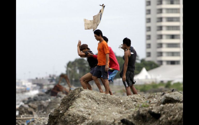 Jóvenes filipinos desafían las fuertes rachas de viento en un pueblo costero en la ciudad de Pasay, al sur de Manila. EFE /