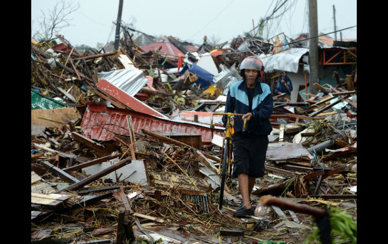 Un hombre camina sobre los escombros de varias casas en la región de Tacloban. AFP /
