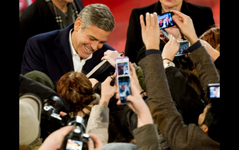 George Clooney, actor de la película 'The Monuments Men', firma autógrafos a su llegada al Festival. AP /