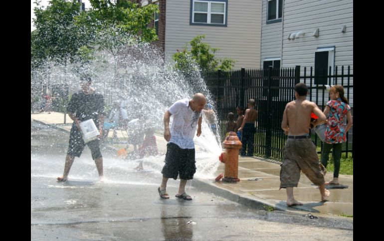 Varias personas juegan con el agua que sale de un hidrante roto. ARCHIVO /