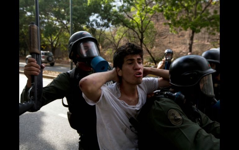 Elementos de la Guardia Nacional Bolivariana detienen a uno de los jóvenes durante el enfrentamiento. AP /