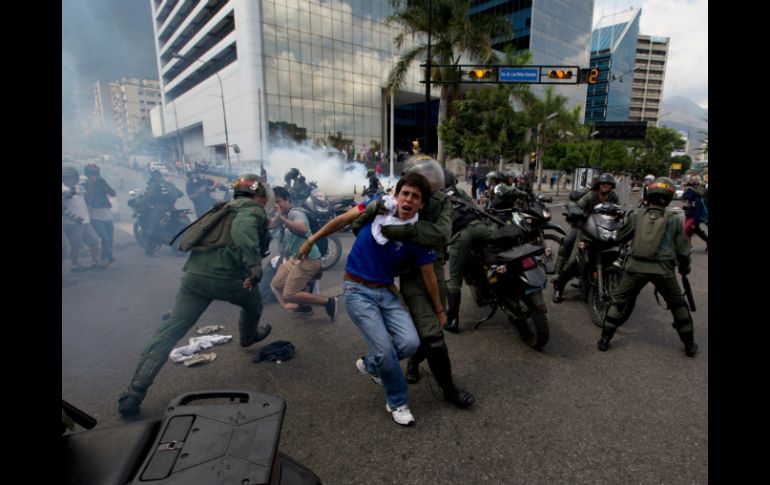 Guardias nacionales lanzan gases lacrimógenos y detienen a manifestantes en la capital venezolana. AP /