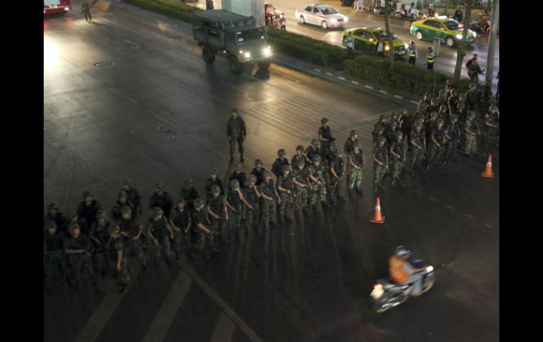 Un motociclista pasa frente al bloqueo preventivo de los soldados en Tailandia. AP /