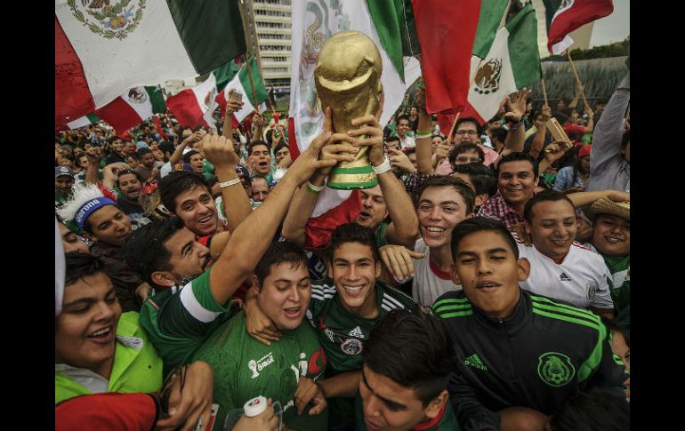 Aficionados sostienen una réplica de la Copa del Mundo.  /