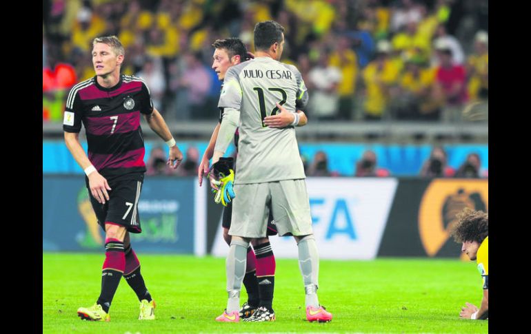 Reconocimiento. Julio Cesar abraza al volante alemán Mezut Özil, mientras David Luiz cae rendido, tras finalizar el juego. EFE /