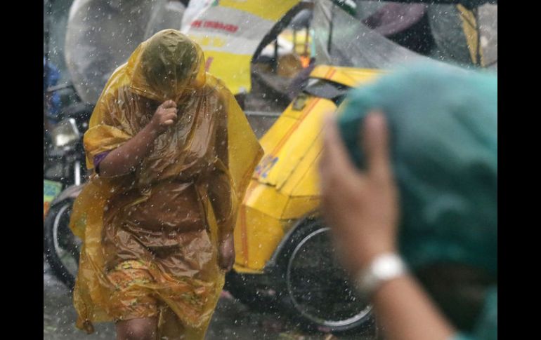 Residentes filipinos intentan protegerse del fuerte viento y lluvia por el paso del tifón ''Rammasun''. EFE /