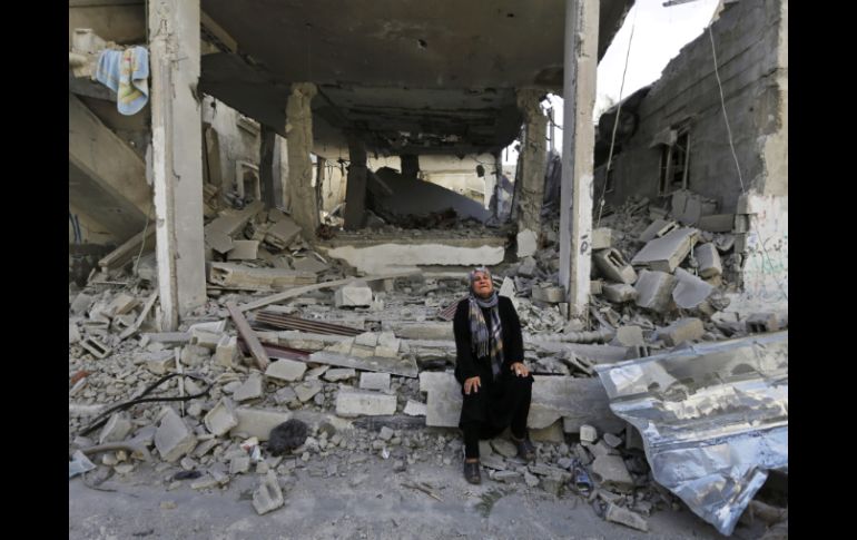 Una mujer palestina llora en los restos de su casa que fue destruida por los ataques israelíes. AP /