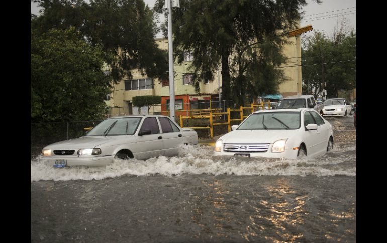 Dos automóviles atraviesan la inundación en Av. Patria.  /