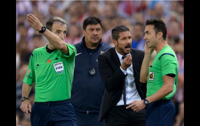 El DT argentino reclama y golpea al cuarto árbitro, Antonio Santos, por lo que fue expulsado del partido. AFP /