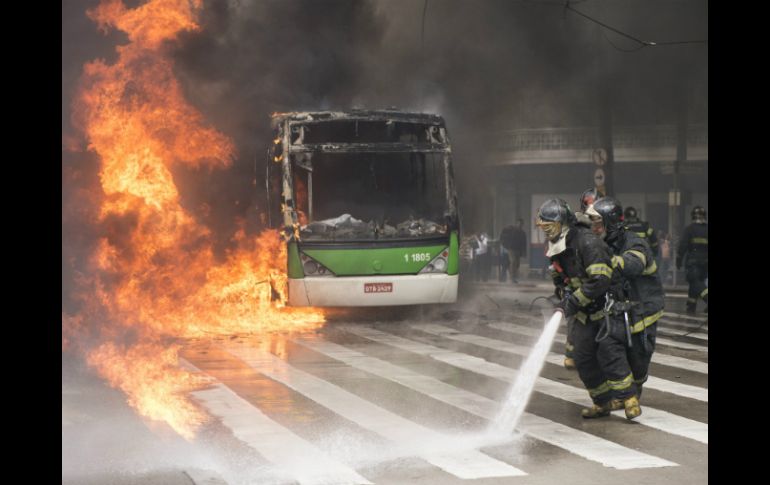 Bomberos apagan un autobús incendiado por manifestantes hoy durante disturbios Sao Paulo. EFE  A. Cadena  /