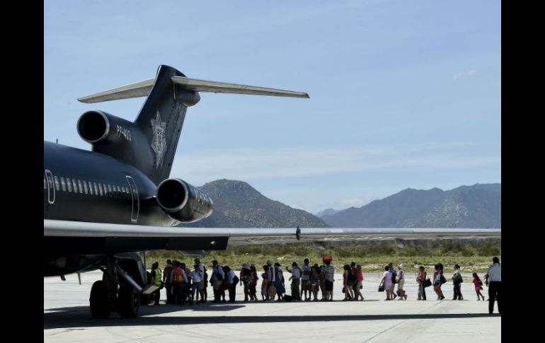 Decenas de turistas varados por el huracán 'Odile' abordan un avión de la Policía Federal para ser evacuados. AFP  R. Schemidt  /