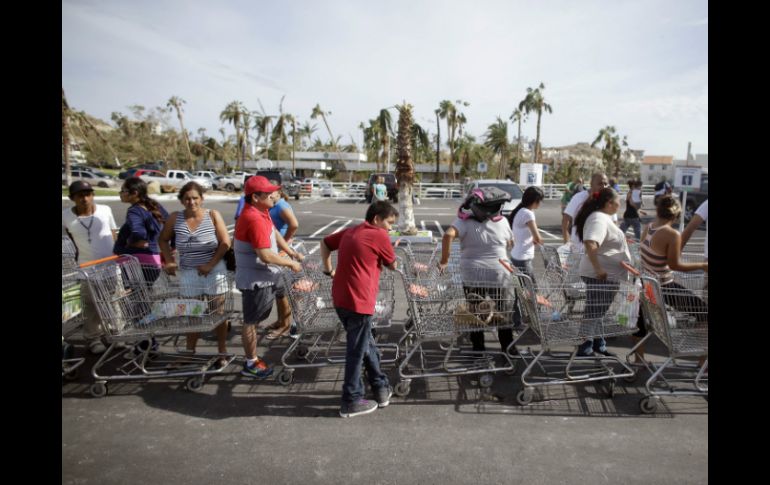Personas hacen fila afuera de un supermercado que donó comida a los afectados por 'Odile'. AP  V. Caivano  /