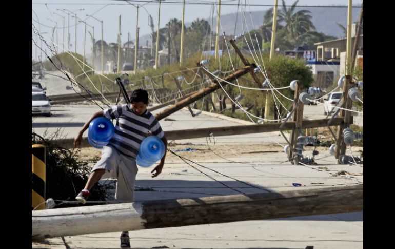 Un hombre camina entre postes derribados por los fuertes vientos generados por 'Odile'. EL UNIVERSAL  J. Serratos  /