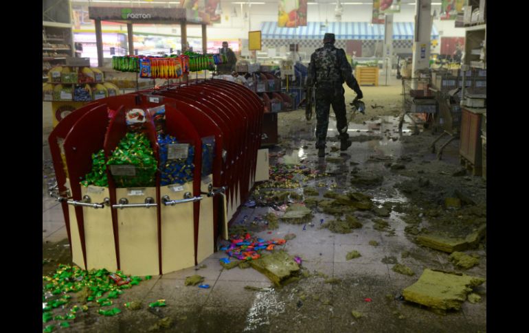 Un separatista prorruso recoge pedazos del misil que cayó en el supermercado. AFP / J. Macdougall