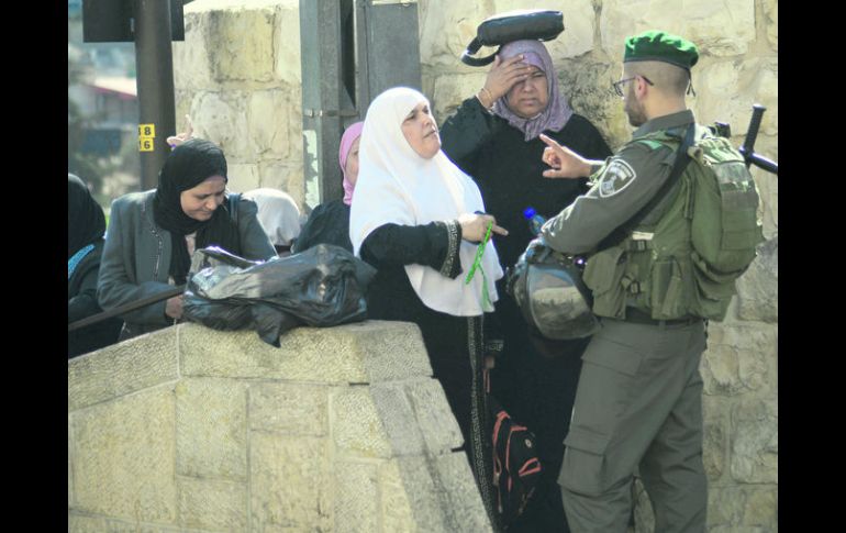 RECLAMO. Mujeres palestinas hablan con un policía israelí tras el cierre de la mezquita de Al-Aqsa. AP /