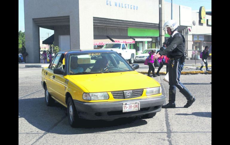 'Oríllese'. Un agente de Movilidad aborda a un taxista para revisar el uso del medidor del servicio de traslado. EL INFORMADOR / A. Hinojosa
