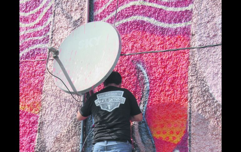 Uno de los jóvenes plasma imágenes sobre la fachada de un edificio en San Pedro Tlaquepaque. ESPECIAL  /
