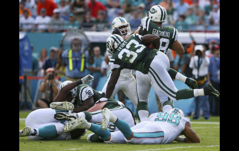 El corredor Chris Ivory (33) de los Jets de Nueva York, salta por encima de la defensa de los Delfines de Miami. AFP / M. Ehrmann