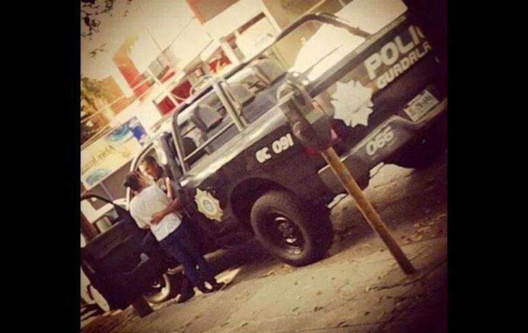 El policía se encontraba sentado en la patrulla mientras besa y abraza a una mujer que se encuentra fuera de la unidad. TWITTER / @informador_JAL