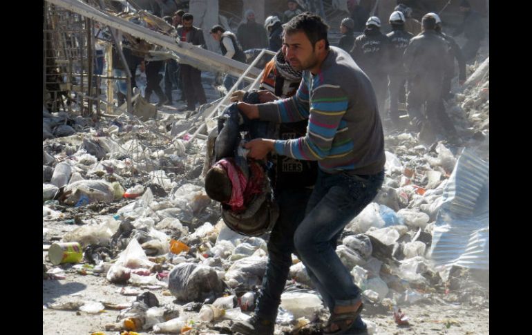 Un hombre sirio carga el cuerpo de una víctima después de un ataque de Al Qaeda. AFP / ARCHIVO