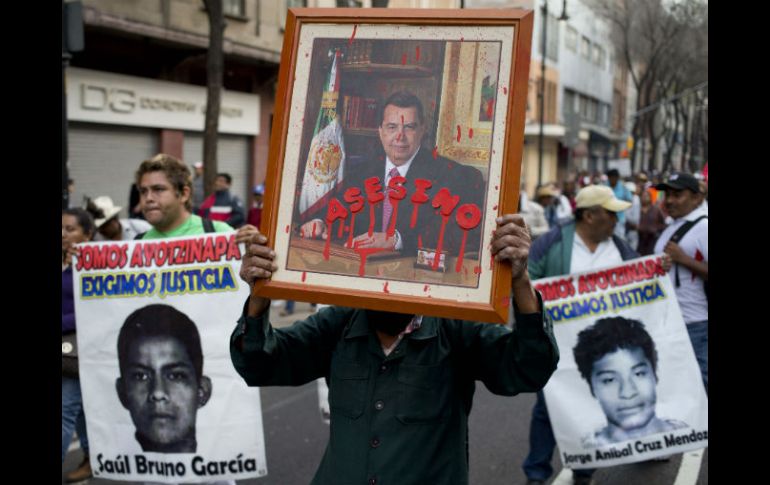Una persona porta un retrato del gobernador con licencia con la leyenda 'asesino' en una manifestación por los 43 de Ayotzinapa. AP / ARCHIVO