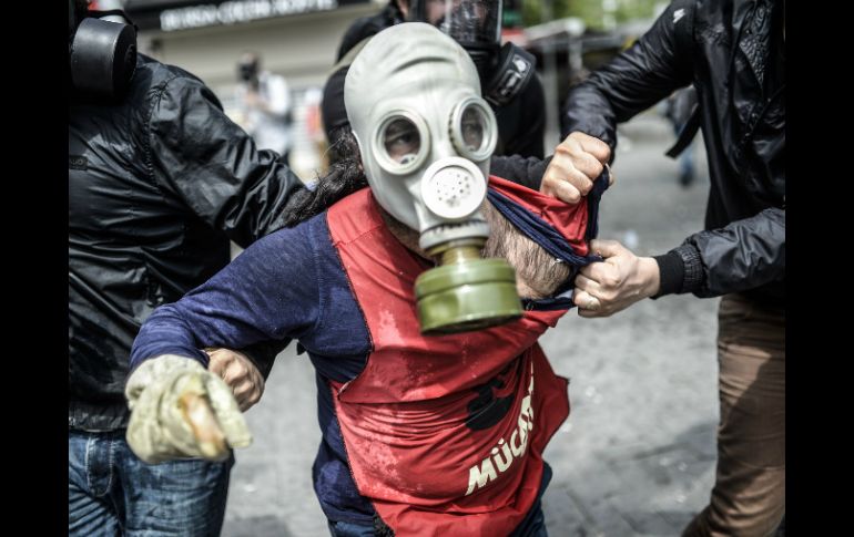 La policía turca detienen a un hombre que protesta cubriendo su rostro con una máscara de gas durante el 1 de mayo. AFP / B. Kilic
