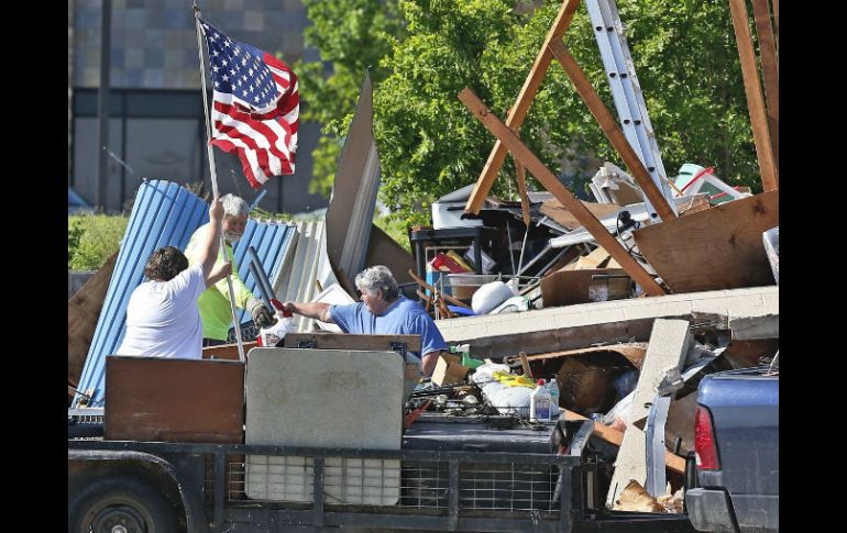 Ciudadanos de Oklahoma recogen sus pertenencias al tiempo de izan la bandera de Estados Unidos. AP / S. Ogrocki