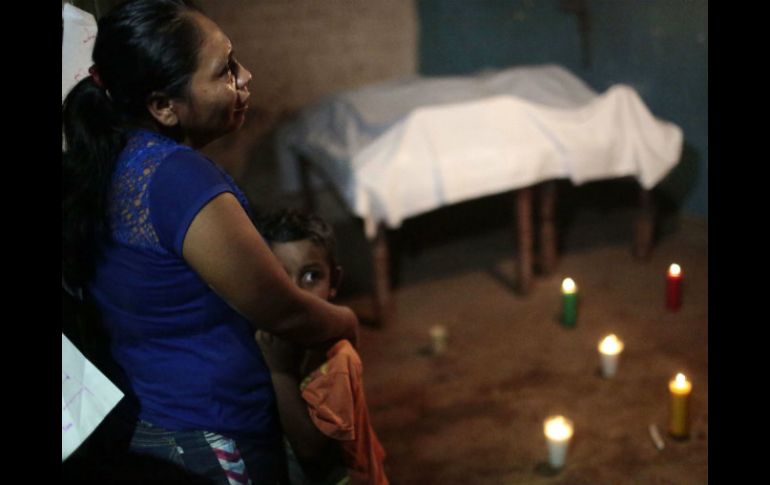Una mujer, junto a un niño, llora cerca de los cuerpos de tres víctimas luego del enfrentamiento de Xolapa. AFP / P. Pardo