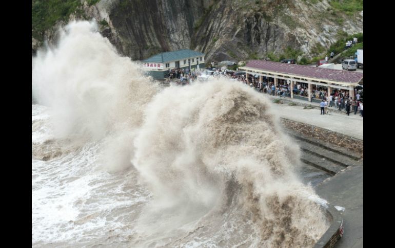 Varias personas observan las enormes olas mientras el tifón Chan-hom se acerca a Wenling, en la provincia Zhejiang. AFP / STR