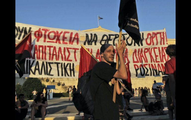 Varias personas participan en una protesta fuera del Parlamento de Atenas contra las políticas de austeridad. EFE /  O. Panagiotou