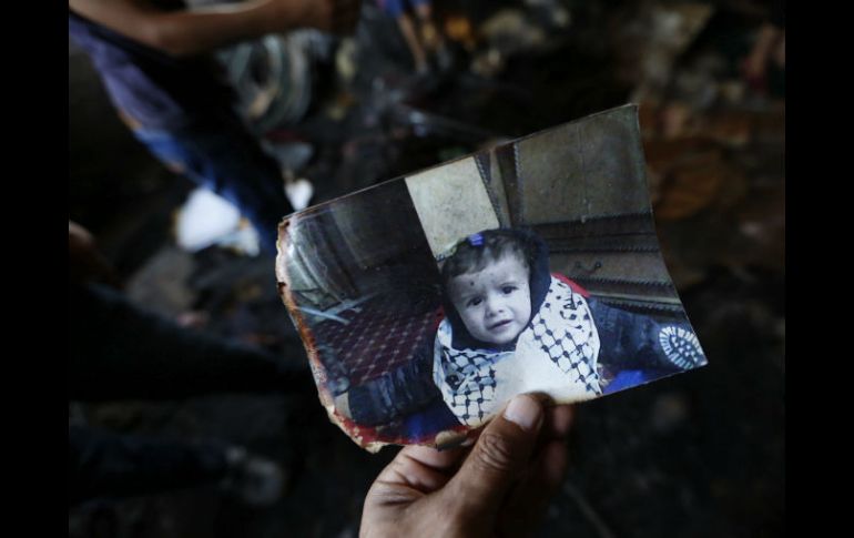 Un familiar muestra una fotografía de Ali Dawabsha, bebé que murió en su casa en un incendio provocado por extremistas israelíes. EFE / A. Badarneh
