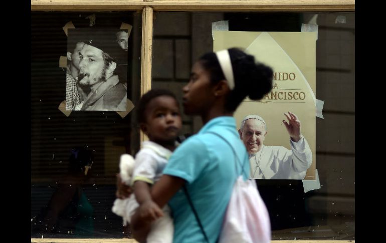 Una mujer con su bebé pasa delante de un cartel alusivo a la visita del Pontífice. AFP / F. Monteforte